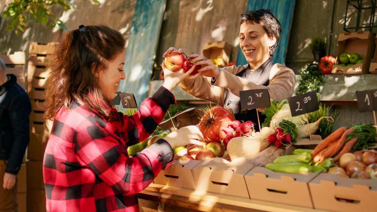 women exchanging goods at farmers market